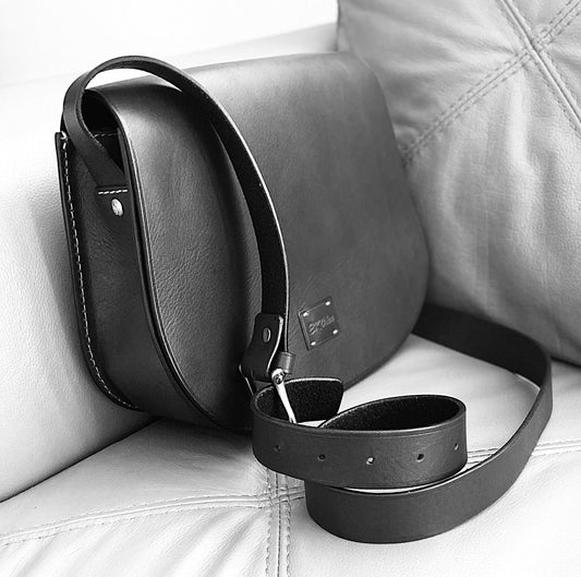 Black full-grain Italian leather bag by EKOńeu resting on a leather sofa