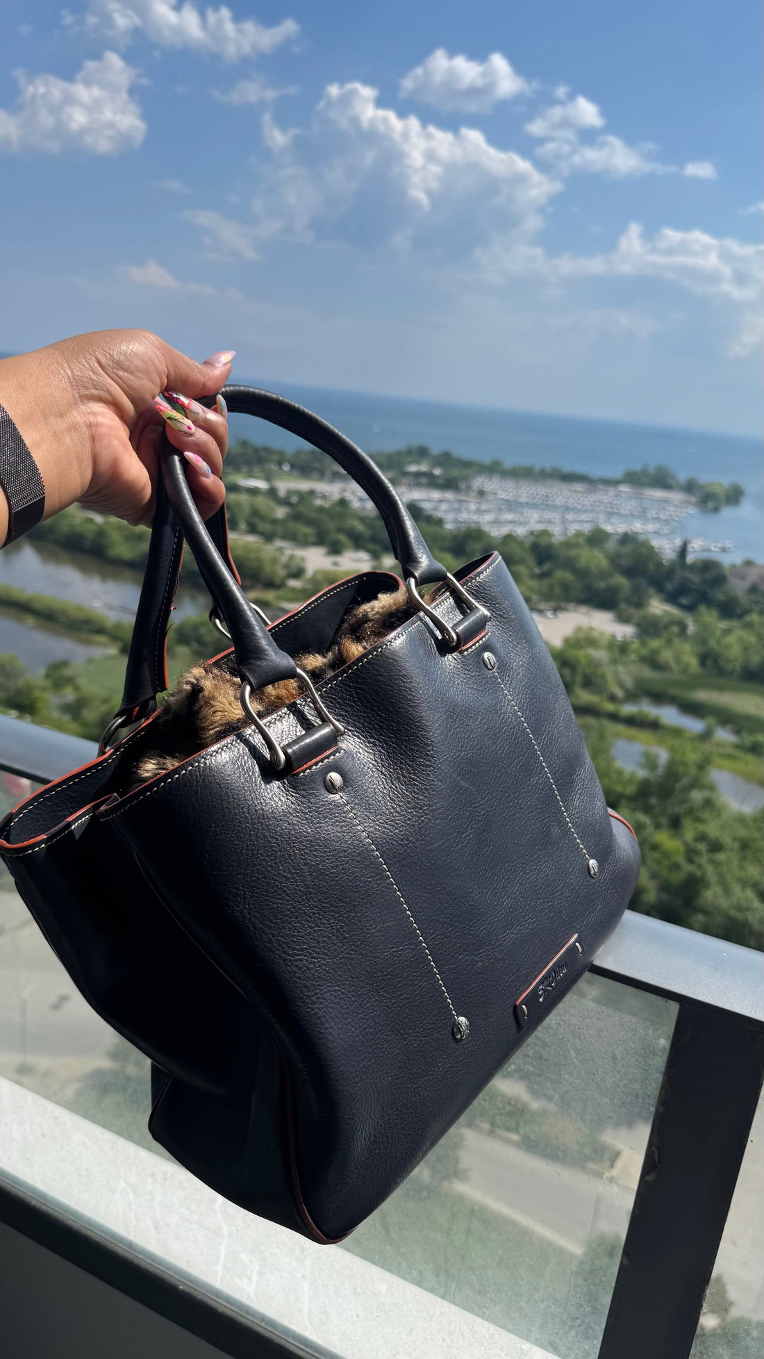 Allegra Italian leather tote bag held against a stunning lakeside skyline