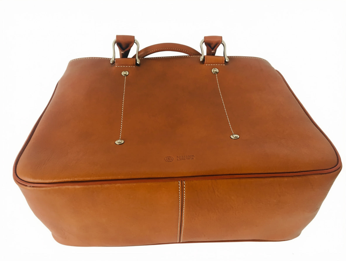 Low-angle view of tobacco Allegra leather tote bag showing the base panel, centre seam, contrast stitching, and metal handle attachments.