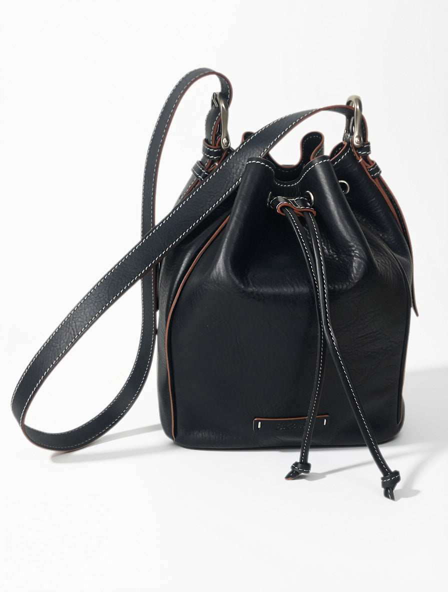 Blue Febe leather bucket bag with drawstring closure, contrast stitching, and an adjustable shoulder strap.
