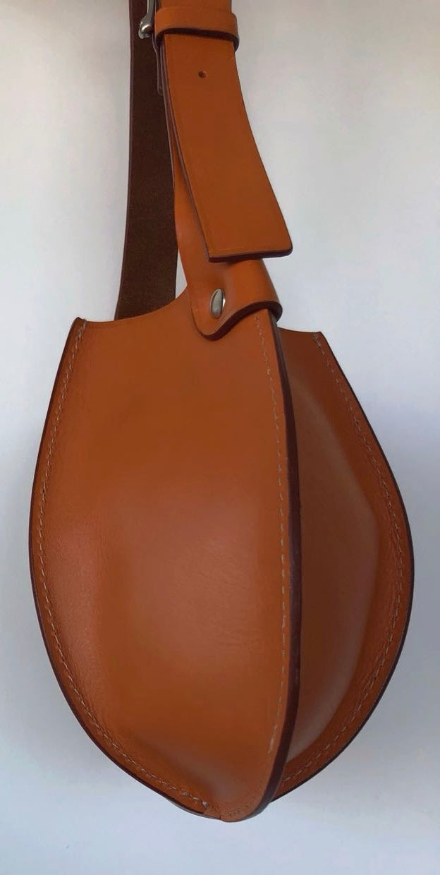 Side view of tobacco Eugenia leather hobo bag showing its curved side panel, depth, stitching, and riveted leather strap attachment.